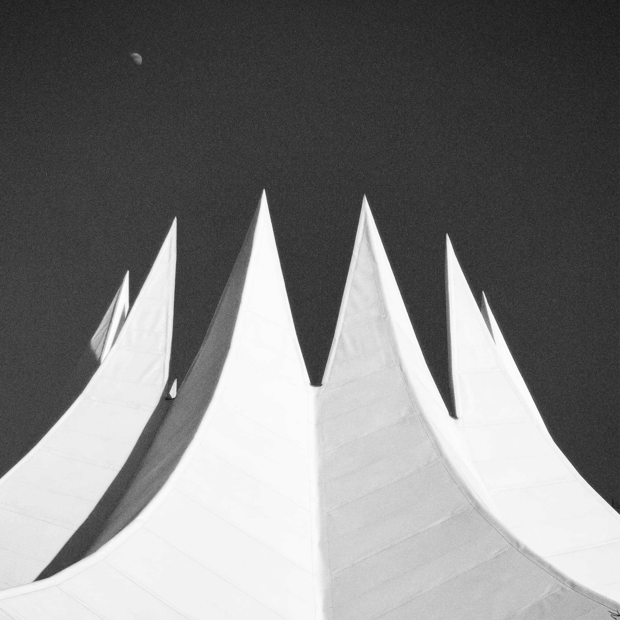 A stark black and white contrast highlights a dramatic, angular archway, evoking mystery and suspense in a minimalist urban setting