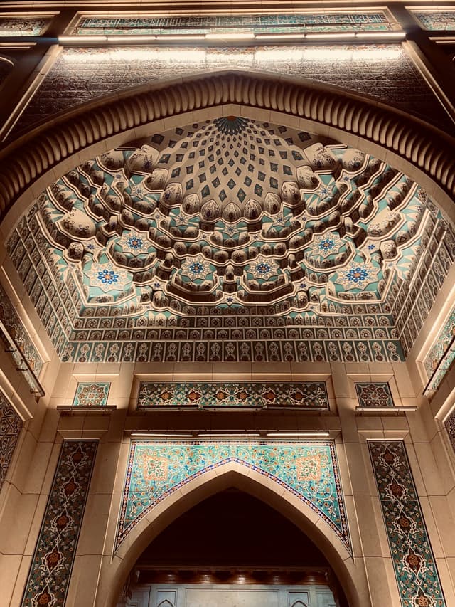 An intricately designed arched doorway, illuminated by warm, golden light, evokes a sense of ancient grandeur and detailed craftsmanship