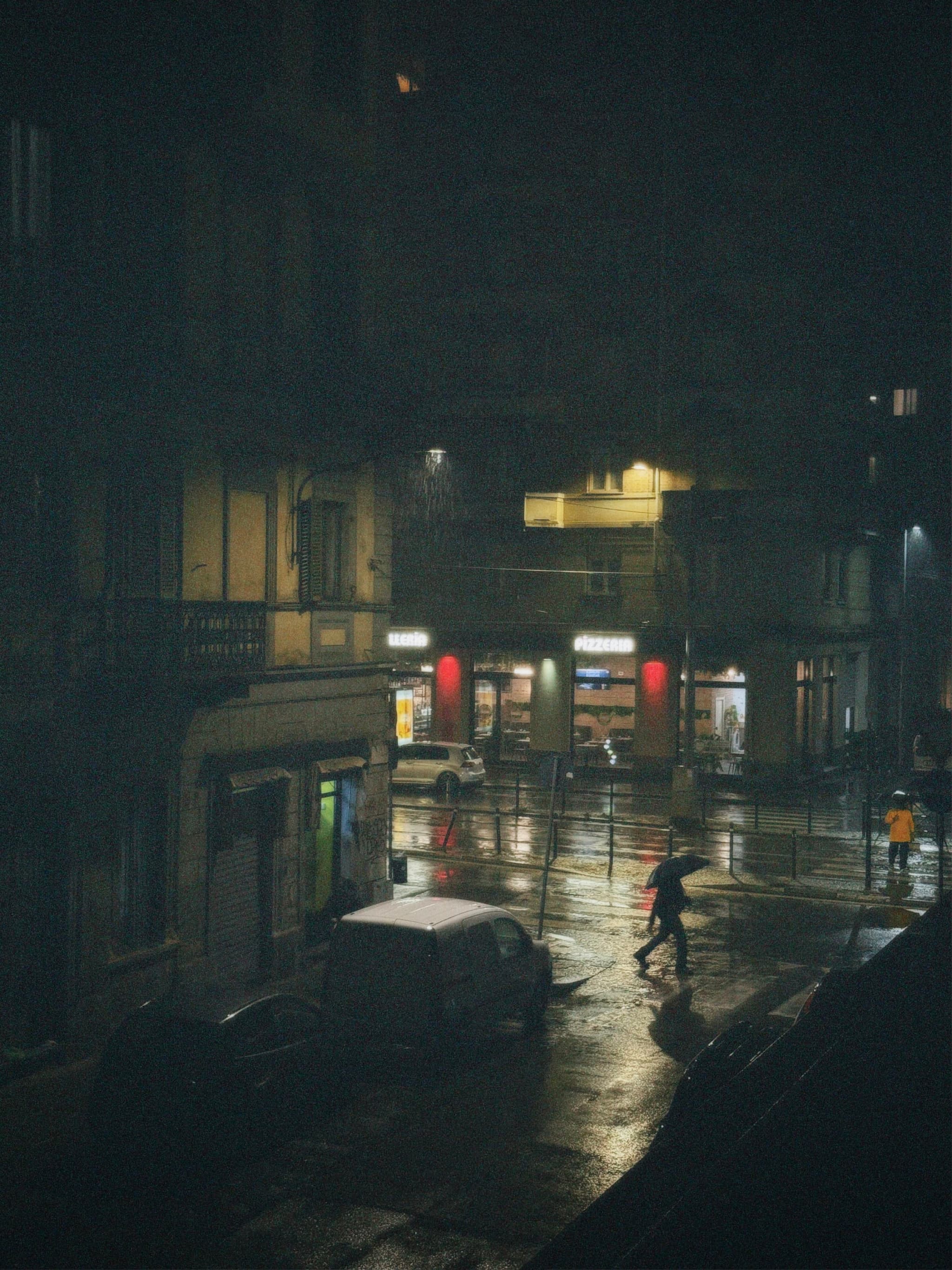 A rainy night in a dimly lit city street, streetlights casting a soft glow, creating a melancholic and introspective atmosphere