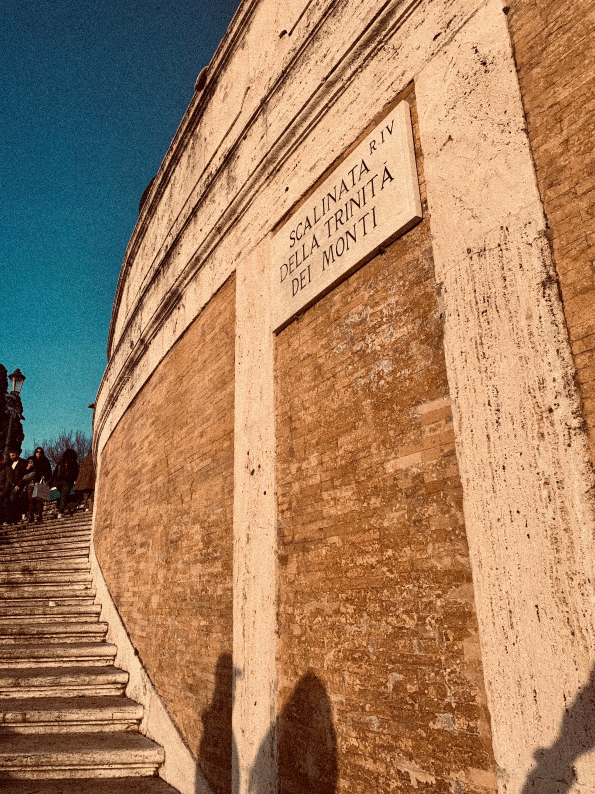 A warm-toned plaque on a weathered stone wall, bathed in golden sunlight, hints at historical significance against a vibrant blue sky