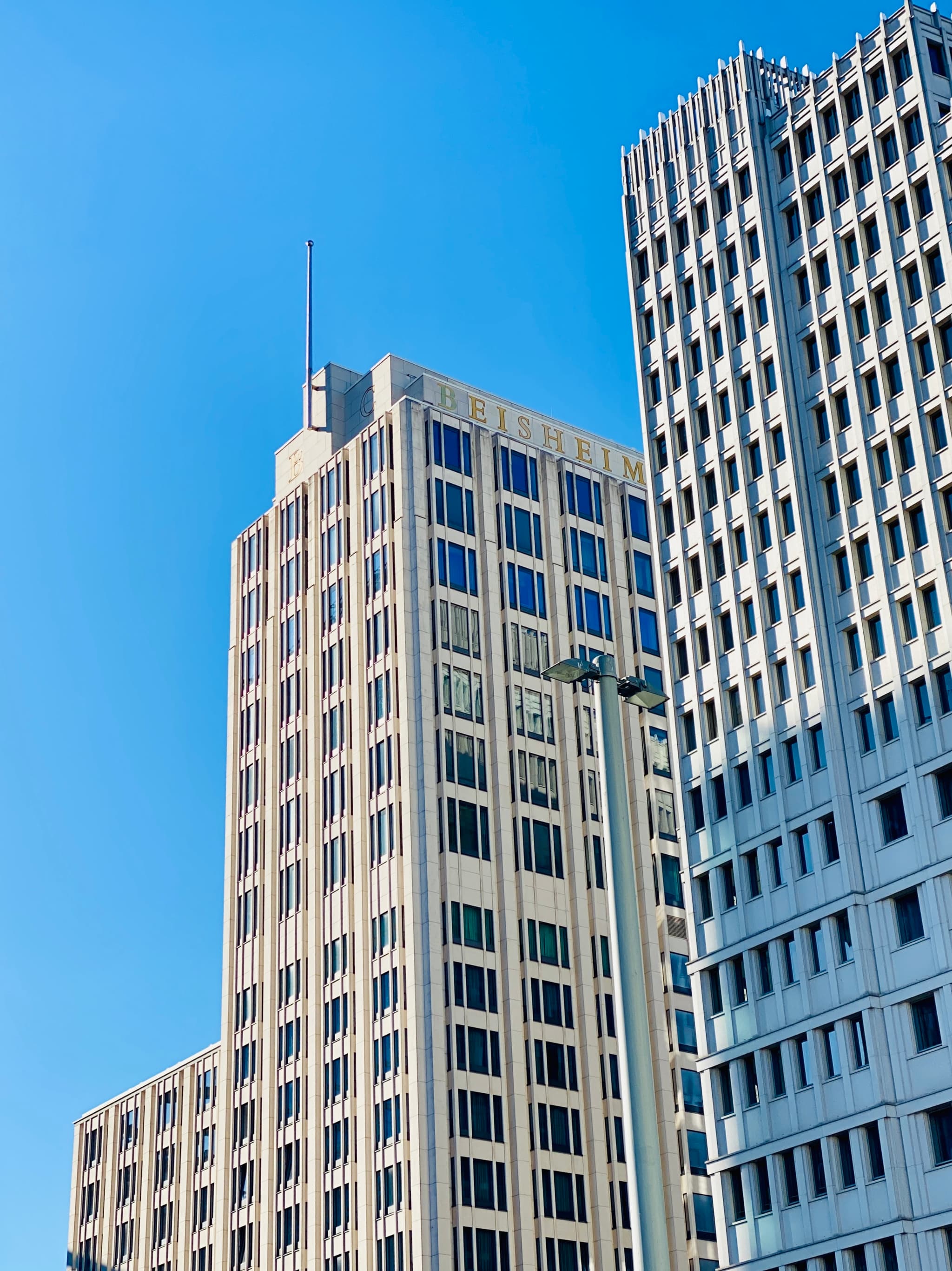 Sunlit skyscrapers stand tall against a vibrant blue sky, creating a modern and urban atmosphere