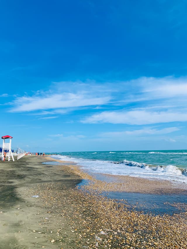A serene beach scene with clear blue sky and gentle waves lapping against a sandy shore, creating a peaceful summer vibe