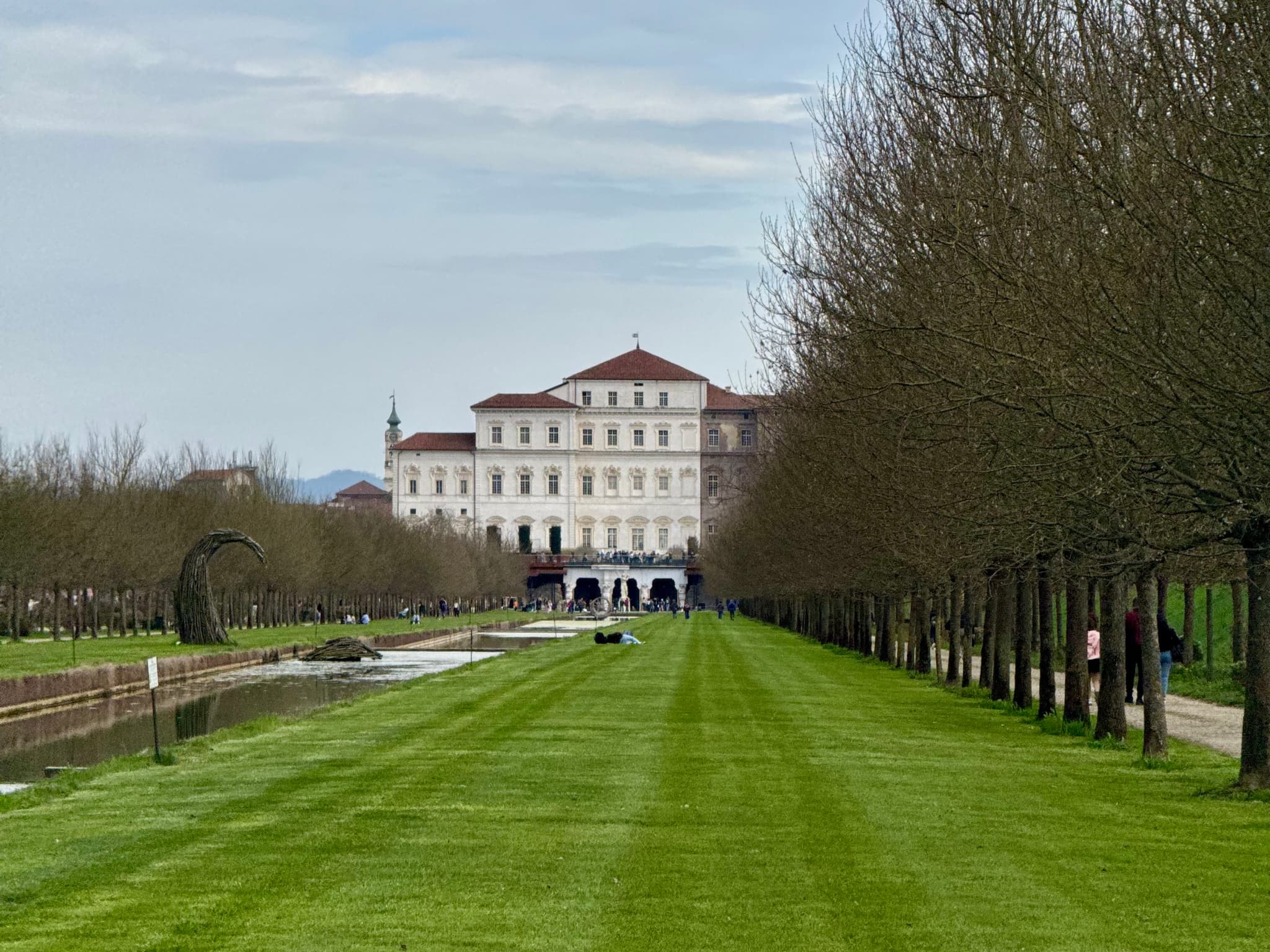 Elegant French château with manicured gardens and tall trees under a bright blue sky, evoking a serene and picturesque atmosphere