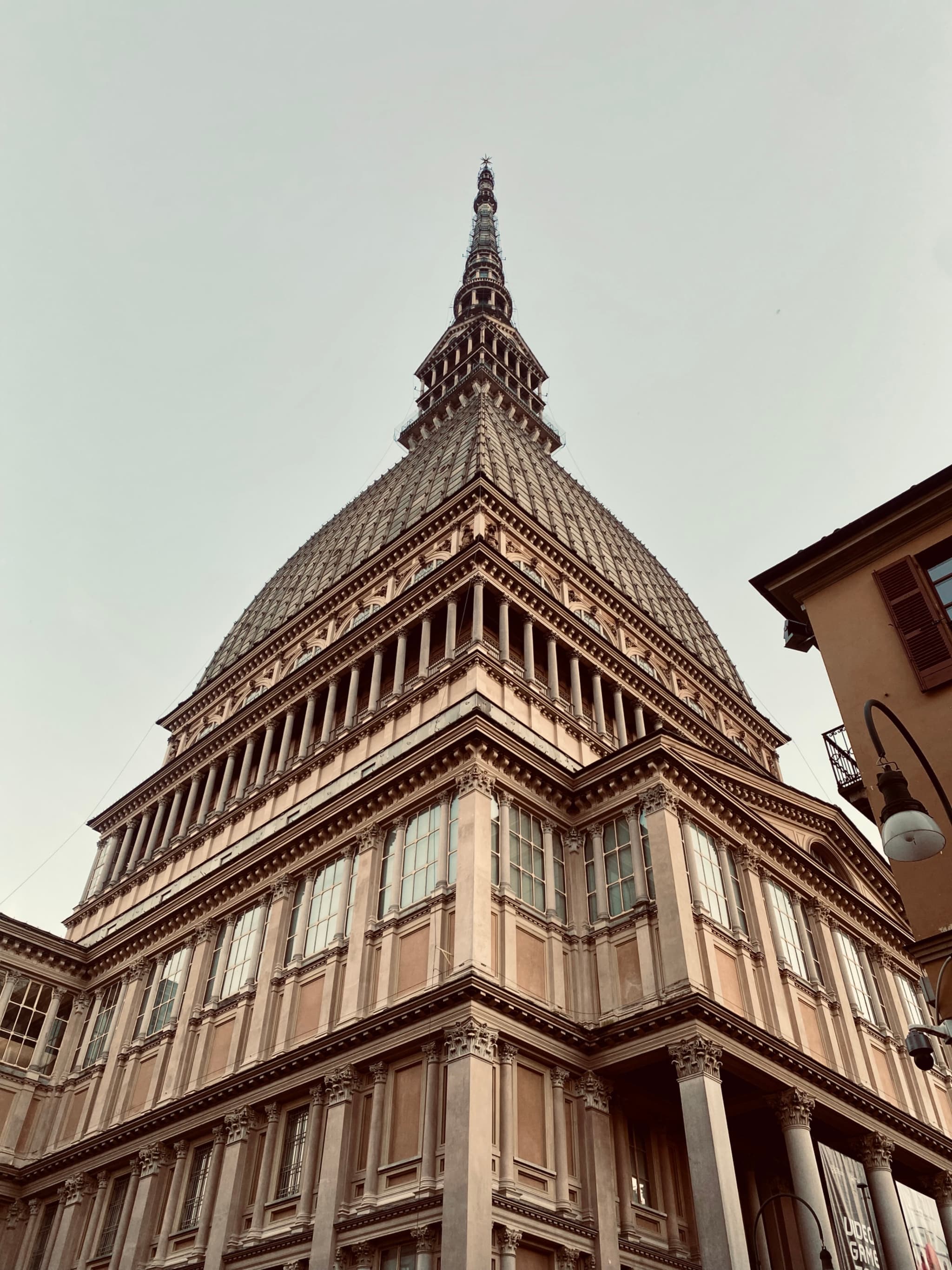 A historic church, Mole Antonelliana, stands majestically against a clear sky in Turin, Italy, with warm lighting and a serene, inviting atmosphere