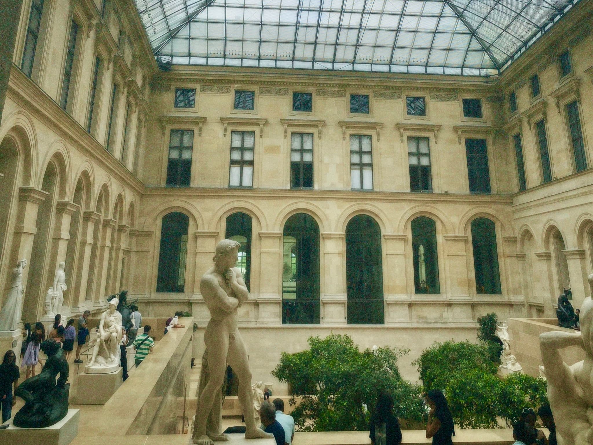 Grand era museum atrium with statues, grand arches, and lush greenery, bathed in soft, even lighting, evoking a serene and majestic atmosphere