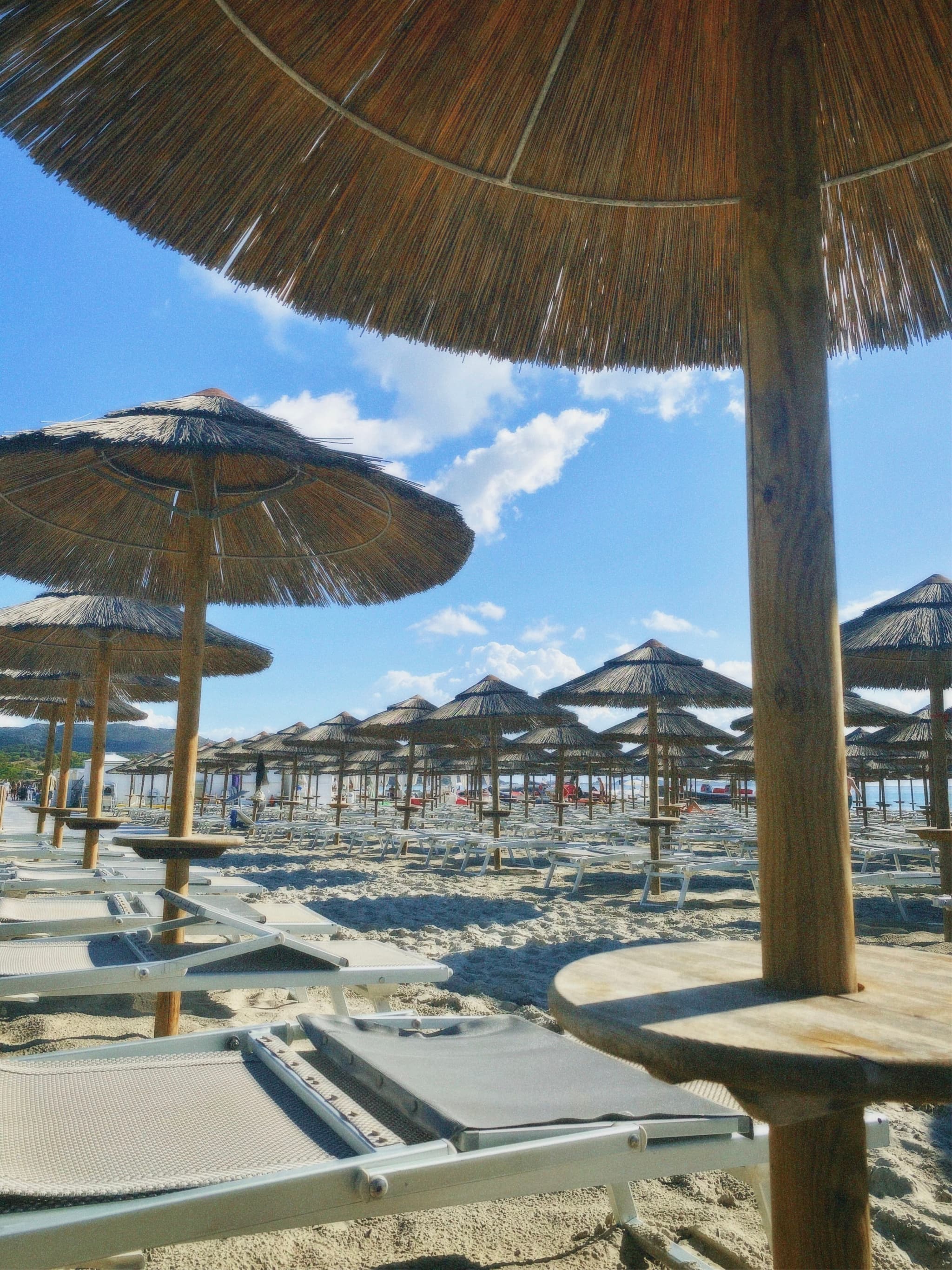 A serene sandy beach under a clear blue sky, with straw umbrellas and sun loungers inviting relaxation