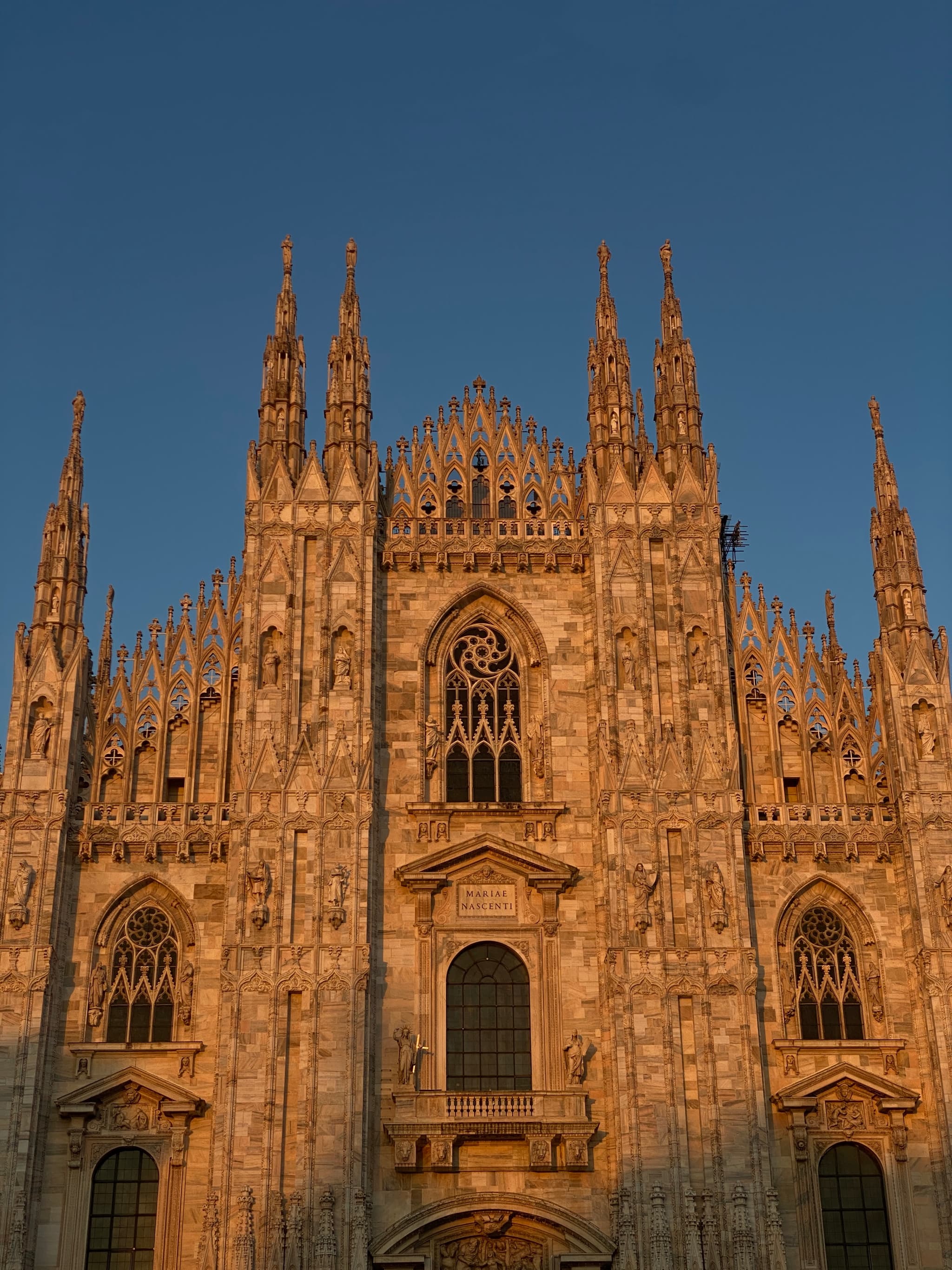 Golden hour sun illuminates the intricate spires and arches of the majestic Milan Cathedral, creating a serene yet majestic atmosphere