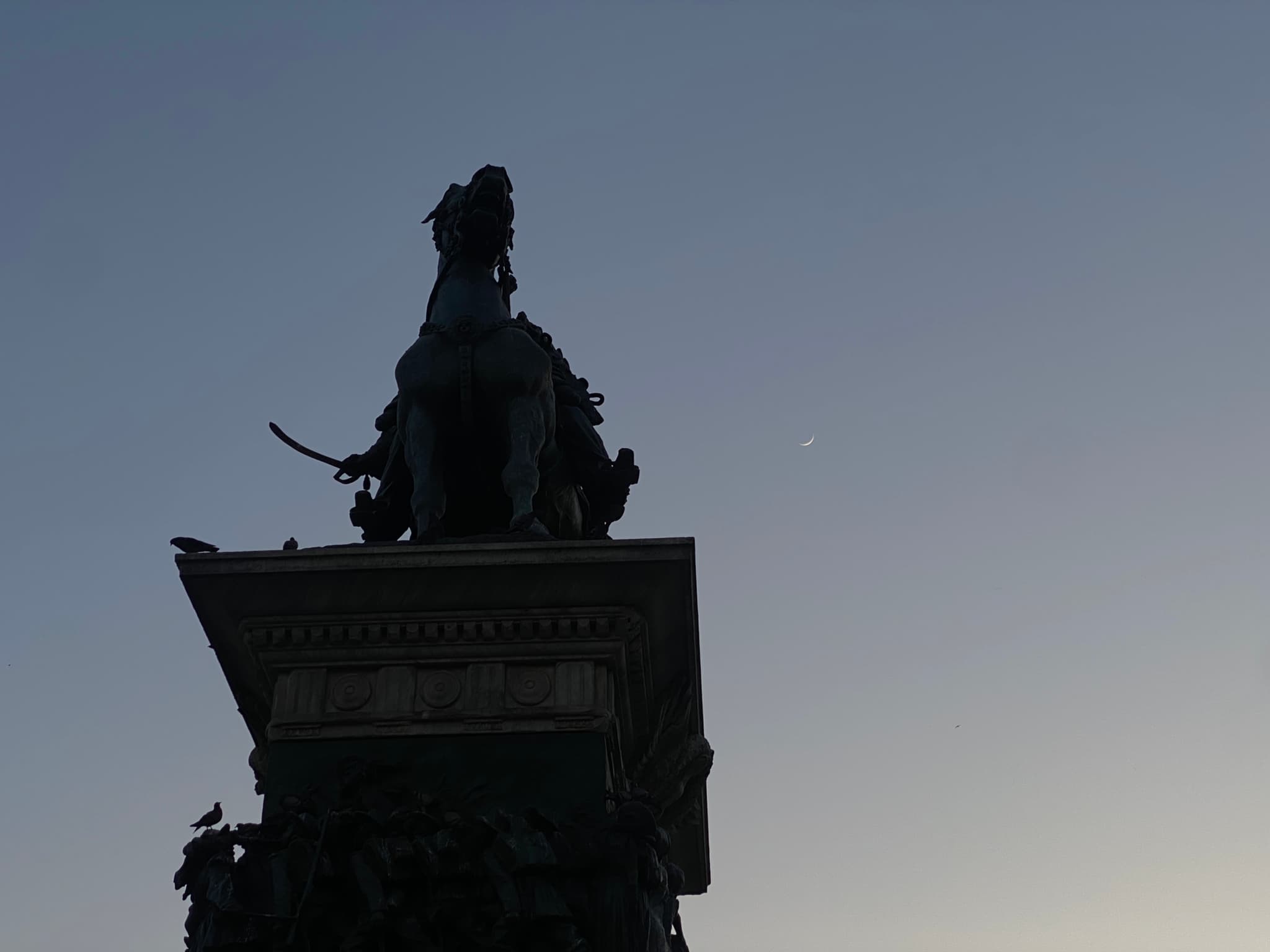 A serene night scene featuring a statue silhouetted against a starry sky, evoking a sense of timelessness and quiet contemplation